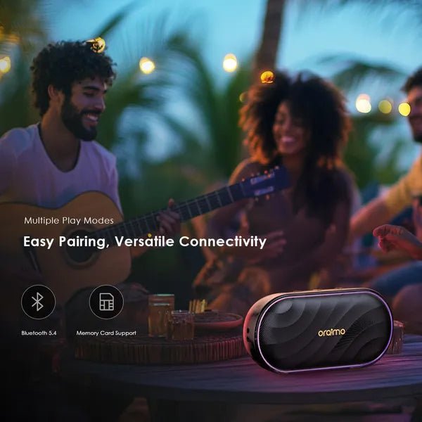 Oraimo SpaceBox 8W FM Wireless Speaker Upto 16 Hours Playtime - Neo Tech AccessoriesGroup of people enjoying music with a oraimo SpaceBox speaker on a table, surrounded by palm trees and lights.